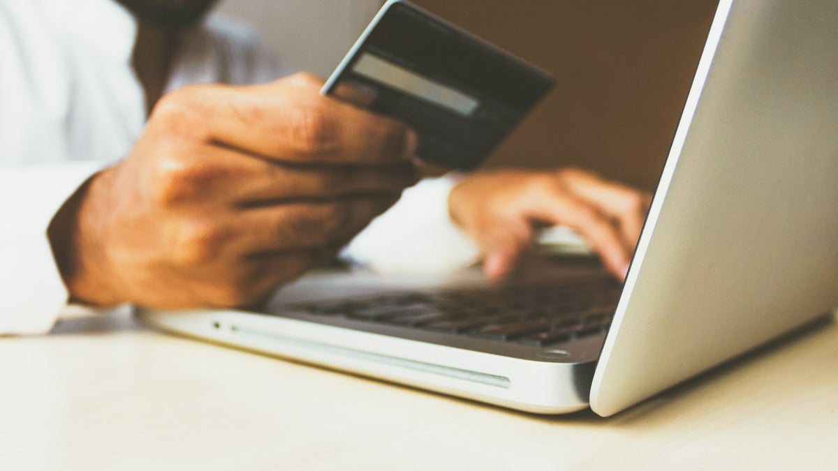 Person shopping online on a laptop holding a payment card